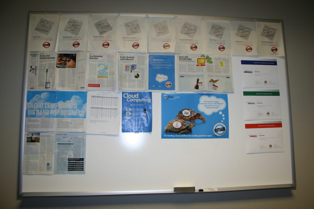 Shell's office wall in 2010 showing Salesforce ads and the certs he earned