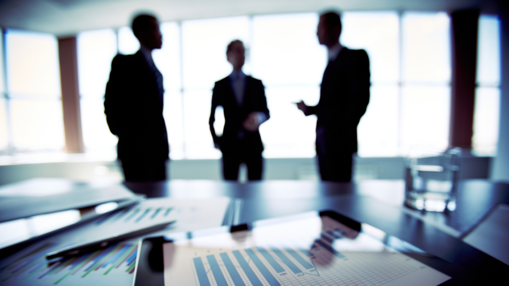 3 business professionals in the background Papers with charts and graphs in the foreground